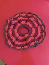 Gomita de pelo tejida al crochet con hilo de algodón a rayas en tonos rosa y violeta, con borde gris.