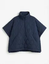 Poncho acolchado color mostaza con cuello alto y abertura frontal con cierre. Presenta un patrón capitoné de formas ovaladas y bolsillos delanteros.