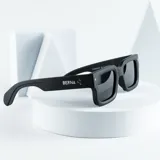 Lentes de sol negros con montura cuadrada gruesa y cristales oscuros.