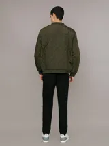 Campera bomber Calvin Klein color verde militar con diseño acolchado en forma de rombos. Tiene cierre frontal con cremallera, cuello, puños y dobladillo acanalados, bolsillos laterales y un bolsillo con cremallera en la manga izquierda con el logo de la marca.