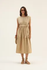 Vestido midi color beige, sin mangas, con lazo en la cintura y bolsillos laterales.
