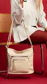 Bandolera beige de símil cuero con dos bolsillos frontales con cierre, un bolsillo trasero, tres bolsillos internos y correa larga regulable.