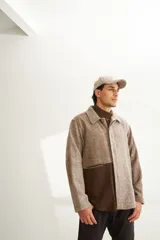 Camisa de hombre estilo leñadora con diseño patchwork en tonos beige y marrón. Presenta coderas, cartera americana y bolsillo ojal en el delantero. Confeccionada en lana fina sin teñir.