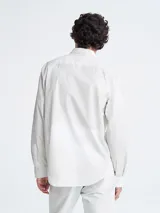 Camisa blanca de manga larga con cuello clásico y cierre con botones.