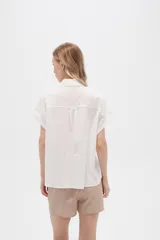 Camisa blanca de algodón con cuello clásico, manga corta con botón y cierre frontal con botones de carey.