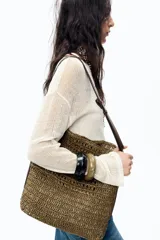 Bolso tipo saca de rafia color marrón con asa de hombro ajustable y detalle lateral. Incluye cartera con bolsillo extraíble y cierre con botón imantado.