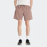 Short deportivo color marrón claro, con cintura elástica ajustable con cordón y logo de New Balance estampado en la pierna izquierda.