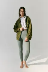 Buzo verde militar de algodón rústico con capucha, corte oversize, cierre metálico, bolsillos delanteros, estampa en frente y espalda, cordón con puntera de goma y lavado acid wash suave.
