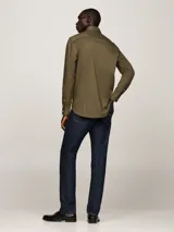 Camisa verde militar de corte regular, con cuello abotonado y mangas largas con puños abotonados. Logo de Tommy Hilfiger bordado en el pecho.