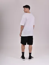 Remera blanca de corte recto con estampado de un auto clásico frente a un skyline urbano.