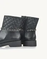 Bota corta negra de cuero con caña acolchada con diseño de rombos, detalle de cadena plateada y suela track con tachas.