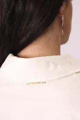 Camisa celeste de corte amplio, con cuello clásico, cierre frontal con botones y bolsillo en el pecho.