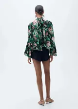 Blusa de gasa con estampado floral, cuello alto, manga larga con volantes y cierre de lazo en la parte posterior.