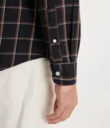 Camisa de franela a cuadros color negro, con botones blancos y corte clásico.
