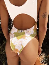 Entero de baño con recorte en la panza y en la espalda. La parte superior es de terciopelo blanco y la parte inferior es de lycra estampada con flores en tonos naranja y verde.