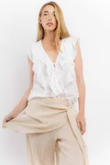 Blusa blanca de algodón con escote en V, volados en el frente y mangas cortas.
