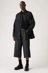 Pantalón capri de denim negro con corte amplio, tiro alto y cinturón de tela con hebilla metálica.