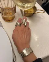 Anillo de diseño orgánico y macizo, realizado artesanalmente en bronce. Presenta una estructura abierta con dos piezas de forma irregular y textura rugosa.