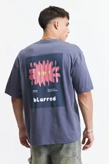 Remera oversize azul con estampado en la espalda de una flor abstracta en tonos rosa y amarillo sobre un fondo azul oscuro.
