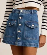 Minifalda de jean azul con bolsillos delanteros con solapa y cierre frontal con botones.
