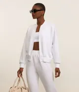 Campera deportiva femenina, modelo bomber, color blanco, con cuello mediano, mangas largas y cierre por cremallera.