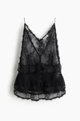 Top negro de breteles finos, confeccionado en encaje floral transparente. Presenta escote en V con botones forrados al frente, un ribete de volados bajo el busto y un segundo volado doble en el bajo.