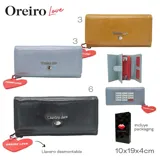Billetera de cuero color camel con cierre de solapa y broche a presión. Logo de la marca en metal plateado y dije colgante en forma de corazón.
