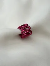 Anillo de aluminio color fucsia con forma ondulada.