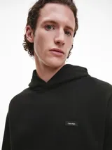 Buzo negro con capucha y bolsillo tipo canguro. Logo de Calvin Klein bordado en el pecho.
