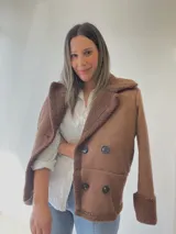 Chaqueta marrón con forro tipo corderito, doble botonadura y cuello con solapas.