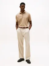 Chomba color beige con patrón integral de logos bordados, cuello tipo chomba, cartera de dos botones, corte clásico y manga corta.