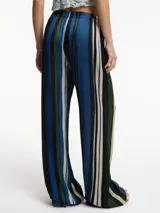 Pantalón de tiro alto con estampado a rayas verticales en tonos rojo, azul, marrón y beige. Tiene bolsillos laterales ocultos y corte amplio.