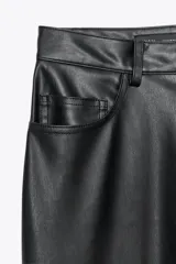 Pantalón negro de tiro medio, con trabillas en la cintura, cinco bolsillos y pernera ancha. Cierre frontal con cremallera, botón oculto y gancho metálico.