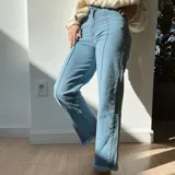 Pantalón de jean celeste, de corte recto, tiro alto y terminación desflecada.