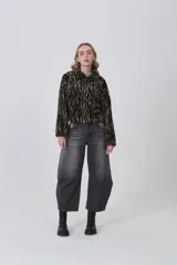 Campera corta de tejido peluche (corderito) con cierre frontal y cuello camisero. Presenta un estampado animal print de cebra o tigre en tonos marrón claro y negro.