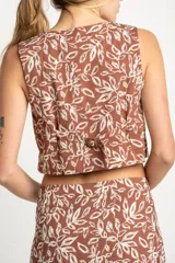 Chaleco marrón con estampado de hojas blancas, escote en V y lazo ajustable en el centro.