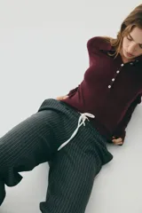 Sweater de punto fino color bordó, con cuello polo y tapeta de botones. Presenta hombros ligeramente caídos y remates acanalados en puños y bajo.