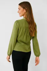 Blusa verde oliva de viscosa con bordado floral en el pecho, cuello mao con volados y mangas largas abullonadas. Cierre frontal con botones. Corte holgado.