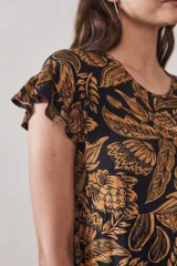 Vestido midi de viscosa con estampado floral en tonos ocre sobre fondo negro. Tiene corte evasé, mangas cortas con volados y largo hasta la rodilla.