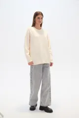 Sweater color crema, de corte holgado, con cuello redondo y mostacillas decorativas.