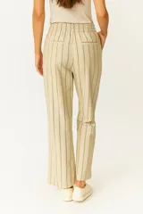 Pantalón de algodón color beige con rayas verticales finas en color negro, de corte holgado y tiro alto, con elástico y cordón ajustable en la cintura.