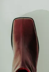 Bota corta de cuero color bordó con acabado natural, caña ajustada y punta suavemente afinada. Posee un taco ancho y estable de aproximadamente 5 cm.