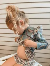 Conjunto de lycra con protección UV, estampado con hojas de palmera y animales de la selva. Incluye remera de manga larga con volados en los hombros y bombacha con volados en la cintura.