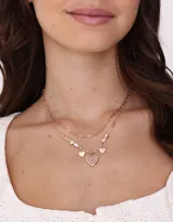 Collar corto dorado con doble cadena, una de eslabones y otra con cuentas y perlas. Incluye dijes de corazones y flores encapsuladas.