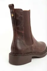 Bota tipo Chelsea de cuero legítimo en color marrón con acabado texturizado. Presenta paneles elásticos laterales al tono, tirador trasero para facilitar el calce y suela de goma gruesa con vira pespunteada.