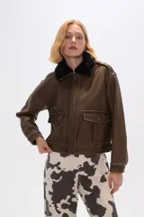 Campera marrón de eco-cuero con cuello de piel sintética negra, cierre frontal con botones a presión, bolsillos con solapa en el pecho y corte holgado.