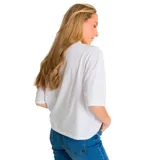 Remera blanca de corte oversize con mangas cortas y cuello redondo. Estampado pequeño en el frente con el logo de Caterpillar y una palmera en color naranja.