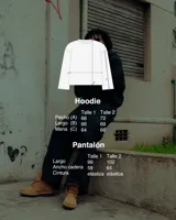 Conjunto deportivo negro, compuesto por un buzo con capucha y bolsillo canguro, y un pantalón de jogging. Ambas prendas tienen estampado puff en el pecho/muslo con el logo de la marca.