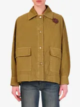 Chaqueta color verde militar con cuello camisero, cierre frontal con cuatro botones metálicos, bolsillos tipo cargo y apliques bordados.
