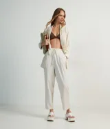 Pantalón fluido color crema, confeccionado en viscolino, con cintura elástica y lazo ajustable.